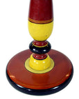 Close-up of a colorful hand-carved India Candle Stick with folk art rings in red, yellow, and black.