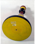 Close-up bottom view of yellow and black hand-carved wooden India Candle Stick with Made in India sticker on base.