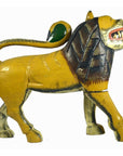Close-up of yellow hand-carved wooden lion with brown mane, green tail, and open mouth showing teeth, India.