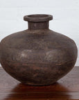 Metal Indian water jar with a generous belly and protruding lip on wooden surface near a white wall, 19th century.
