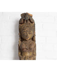 Polychrome wooden hand carved Indian antique statue of celestial musician against a white brick wall background.