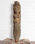 Polychrome hand carved wooden statue of an Indian celestial musician on cloth with a white brick wall background.