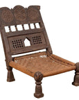 Brown wooden low seat chair with carved rosette details and handwoven rope seat, rustic antique style.