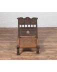Brown wooden low seat chair with carved rosettes and handwoven rope seat, rustic Indian antique style.