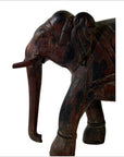 Brown vintage Indian elephant carving with textured details, side view, on a white background.