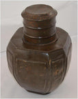 Bronze-colored metal octagonal water jug with wide neck, simple engraved patterns on lid and rim, close-up view.