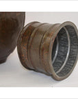 Silver engraved metal bracelet and octagonal Indian metal water jug on white surface, close-up view.