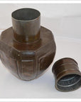 Silver-colored metal octagonal Indian water jug with wide neck and matching lid on a white surface.