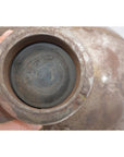Close-up of a hand holding an oval silver metal Indian water jug, antique style.