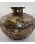 Close-up of a rustic metallic Indian water jug, round-shaped with a small neck and rivet-like details.