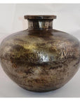 Close-up of a rustic metallic Indian water jug, round-shaped with a small neck and rivet-like details.