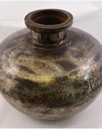 Close-up of a round, tarnished metal Indian water jug with wide neck on a plain background.