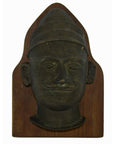 Close-up of dark brass bas-relief plaque showing a sculpted head with pointed hat, 8x4x1.5 inches, very good condition.