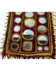 Multicolor hand sewn cloth with mirrored insets, cowrie shell border, and hand finished edges, close-up view.