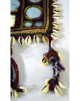 Multicolor hand-sewn Indian cloth with mirrors, embroidery, and cowrie shells, close-up textile detail.