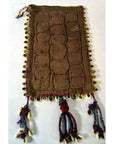 Close-up of rectangular brown fabric pouch with hand-sewn cowrie shells and hanging tassels, vintage Indian style.