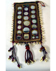 Colorful hand sewn Indian cloth with mirrors, threads, cowrie shells and tassels, close-up textile detail.