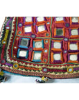 Close-up of a multicolor embroidered fabric pouch with mirror accents and tassels, Indian traditional design.