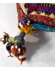 Colorful fabric pouch with traditional Indian embroidery, metal trinkets, and beads on a white background.