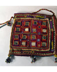 Red embroidered fabric pouch with mirror accents, tassels, and braided drawstrings on a white background, close-up.