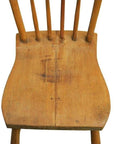 Close-up of a worn wood Indonesian chair seat with visible spindles and scratches on a white background.