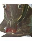 Close-up of brown wood Indonesian deer wall plaque with hand-carved antlers next to weathered wooden duck sculpture.