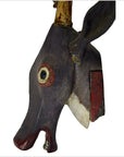 Painted wooden Indonesian deer head trophy with large eyes, long snout, and decorative horns, wall-mounted close-up.