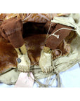 Close-up of wooden Indonesian puppet legs and feet with tangled strings, brown pants, and gold-patterned dress.