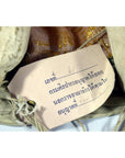 Close-up of handwritten Thai label with museum export permit on Indonesian puppet, paper attached to wood.