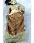 Brown and beige Indonesian puppet made of wood, with articulated fingers and movable mouth, lying on white background.