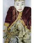 Close-up of Indonesian puppet with painted face, velvet jacket, patterned skirt, and tangled strings.