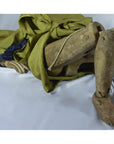 Close-up of Indonesian puppet with tangled strings, green cloth, worn legs and hand, lying on its side.