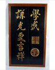 Black lacquered wall panel with gold Japanese calligraphy, two red seals, and a visible vertical crack.