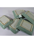 Green celadon ceramic bowls stacked, bottom view, on a white background.
