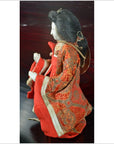 Red and gold kimono Japanese doll, long sleeves, side view.