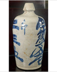 Close-up of a white ceramic Japanese doll with blue calligraphy, narrow neck, Kyoto-inspired design.