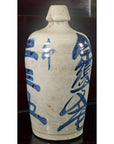 Close-up of a white ceramic Japanese doll with blue calligraphy, narrow neck, Kyoto-inspired design.