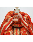 Close-up of a Japanese doll in a red kimono with gold and orange patterns, Kyoto made.