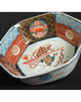 White porcelain Imari bowl with red, blue, and gold floral and geometric patterns, close-up.