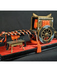 Black lacquered Japanese festival cart with red and gold accents, close-up view.