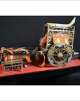 Close-up of a red lacquered Japanese festival cart miniature with ornate patterns and orange tassels, tabletop view.