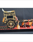 Black and gold Japanese lacquered festival cart with floral accents, tassels, and red and black base on display.