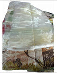 Cream silk sash with shiny finish, white floral pattern, folded on multicolored fabric, 11.5 inches wide.