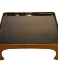 Black lacquered bamboo square tea ceremony tray with curved legs and raised edges, close-up.