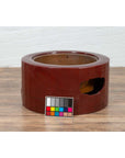 Red lacquered Japanese Taishō circular hibachi on wood floor with color checker card in front, early 20th century.