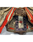 Close-up of red, gold, and purple patterned fabric layers on Japanese Taisho Samurai Doll.
