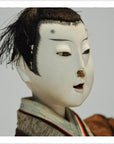 Close-up of Japanese Taisho Samurai doll with pale skin, black hair, and kimono.