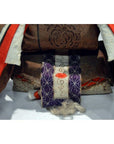 Close-up of Japanese Taisho Samurai doll in brown, purple, red, and white patterned fabric.