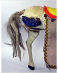 Close-up of a handmade Japanese two-headed horse toy with yarn tail, blue eye, and fabric saddle on white background.