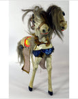 Close-up of Japanese two-headed horse toy with messy gray hair, blue sequin saddle, and decorative harnesses.